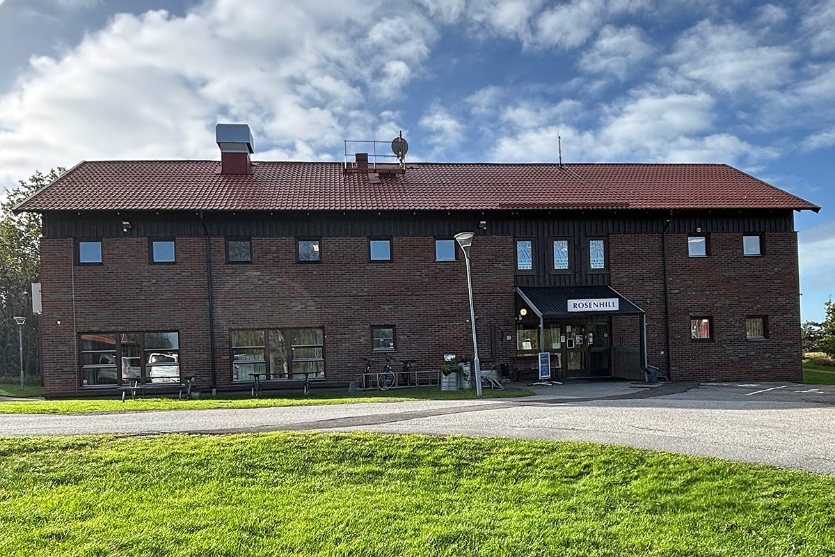 Rosenhills byggnad med grönt gräs i förgrunden och blå himmel ovanför Rosenhills byggnad med grönt gräs i förgrunden och blå himmel ovanför