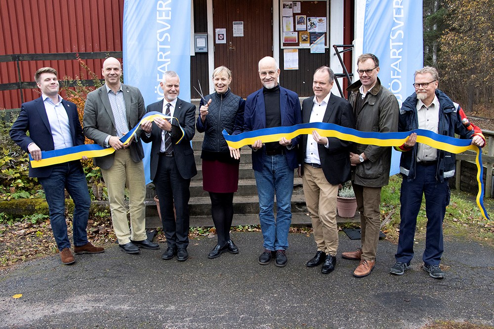 Sjöfartsverkets gd, Katarina Norén, klippte till och så var farleden till Hargs Hamn invigd. Från vänster: Projektledare Max Bjurström, Sjöfartsverket, regionråd Johan Örjes, Region Uppsala, regionala direktören Einar Schuch, Trafikverket Öst, kommunalrådet Jacob Spangenberg, Östhammar, vd Peeter Nömm, Hargs Hamn, produktmarknadschef Per Germundsson, Lantmännen och lotsen Johan Berggren som jobbat mycket engagerat för en säkrare farled. Foto: Agne Hörnestig Flera personer vid invigningen. De håller i ett blått och gult band, som har klippts av av Katarina Norén som står i mitten med en stor sax. Alla ser glada ut..