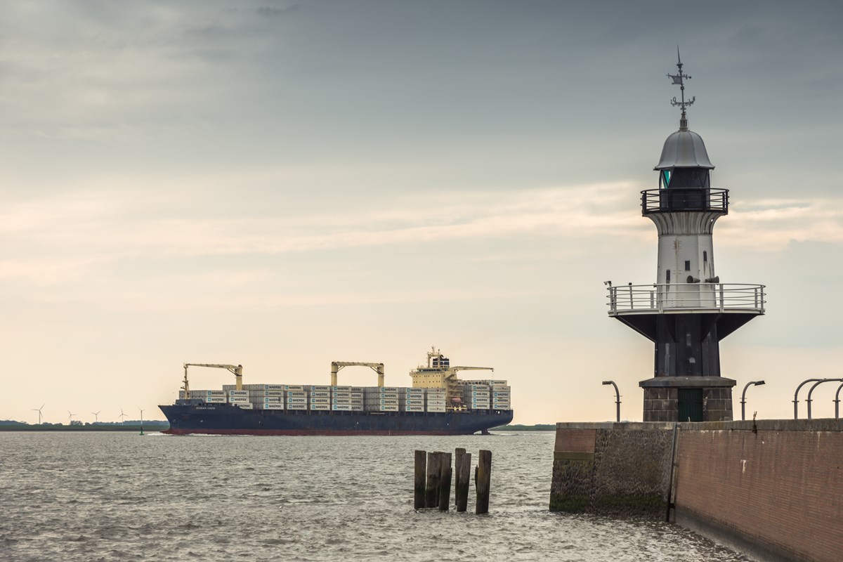 Ett fartyg syns på havet i bakgrunden med en fyr i förgrunden