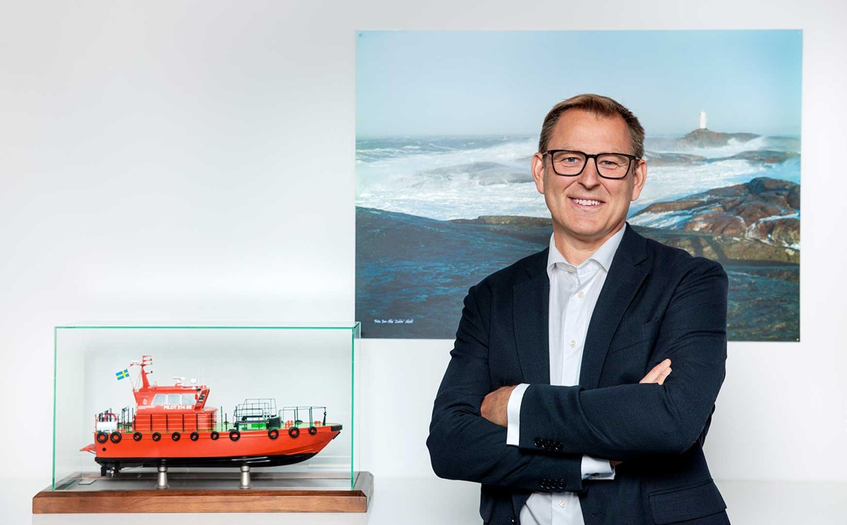 Porträtt på Erik Eklund som står framför en tavla med en lotsbåt i modell bredvid