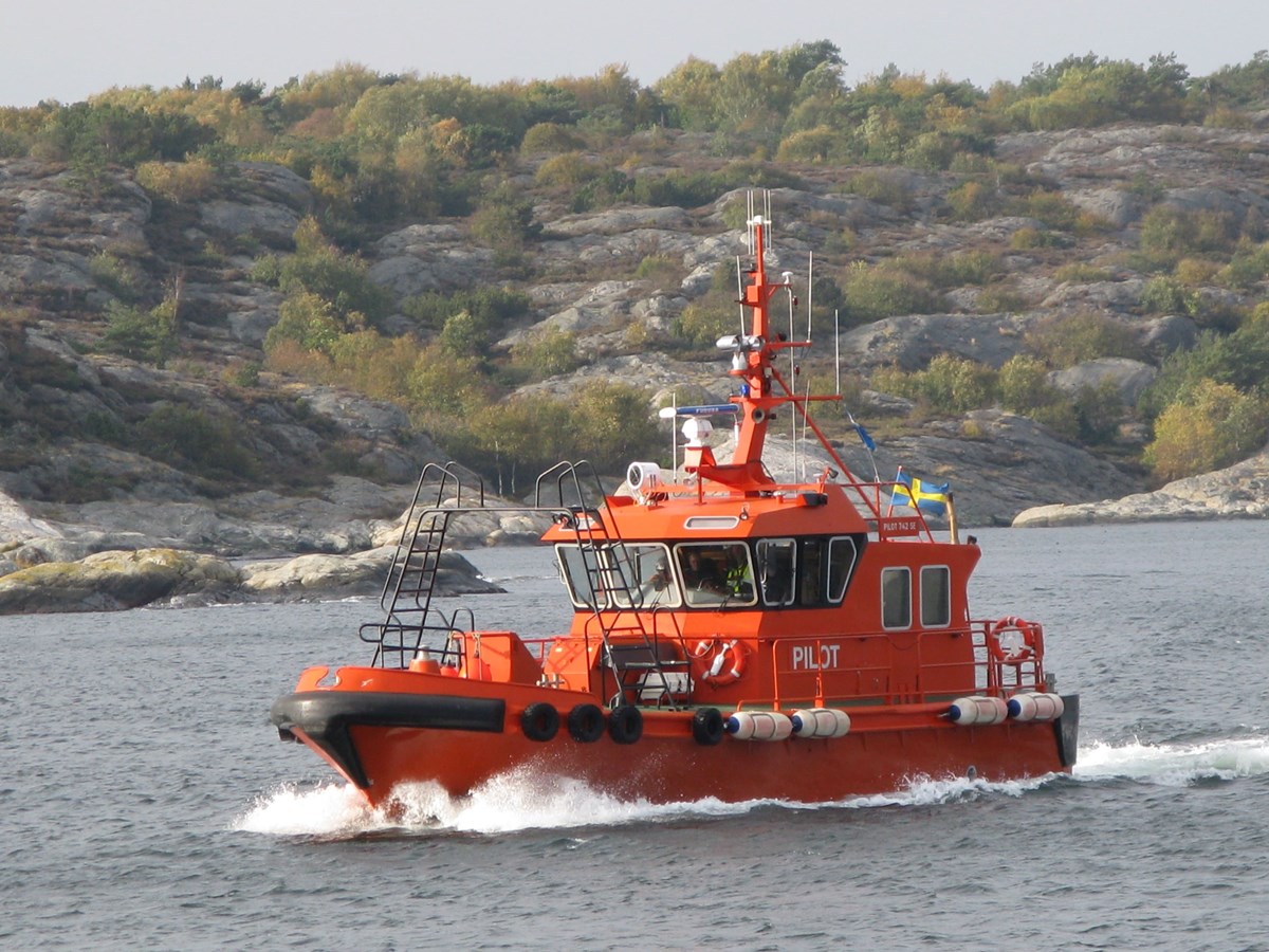 Bild på en lotsbåt med skärgård i bakgrunden