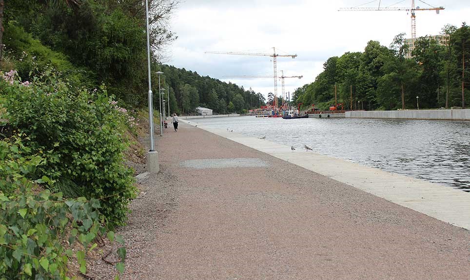 Byggnadsarbete vid Södertälje sluss Bilden visar en promenadväg bredvid slussen i Södertälje. Byggkranar syns över kanalen