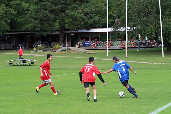 Four football players in the middle of the game. Seamen's Center in the background.