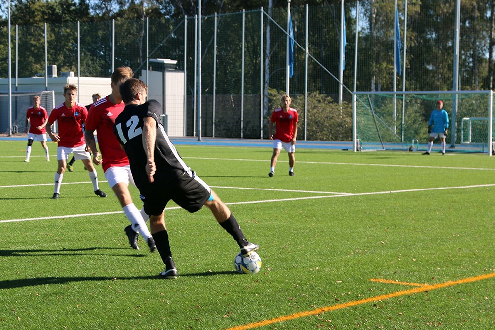 Spelare i svart dress försöker ta sig förbi en försvarare i röd dress