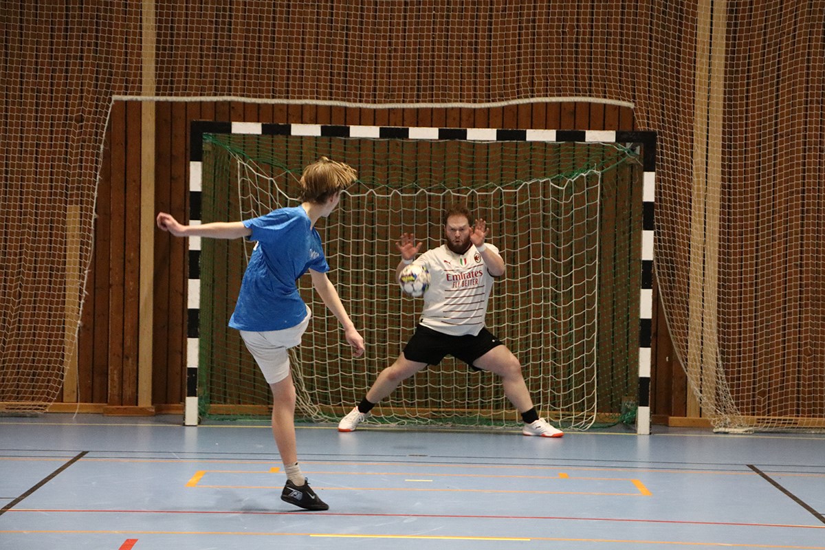En inomhusfotbollsspelare lägger en straffspark mot en målvakt