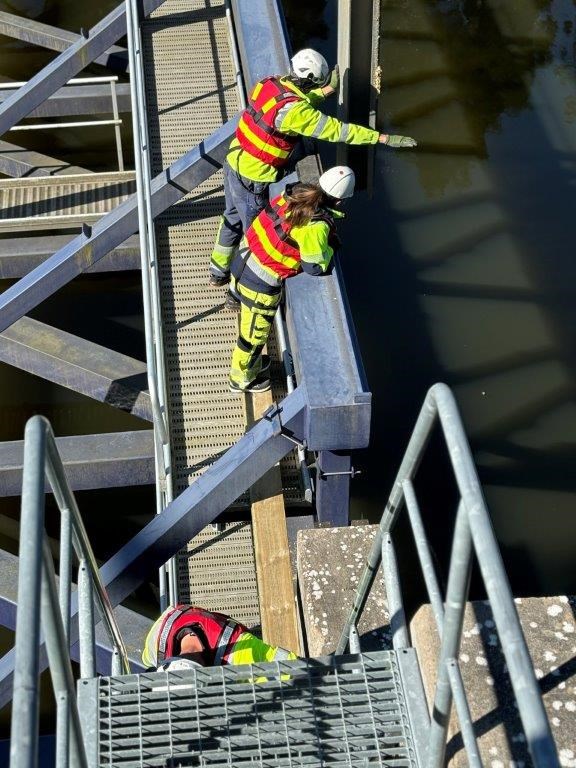 20 man har arbetat med att få sättbron på plats. varselklädda personer på en bro.